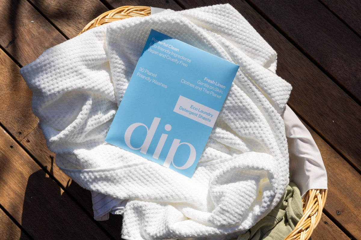 A pack of Dip laundry sheets on clean white towels in a laundry basket